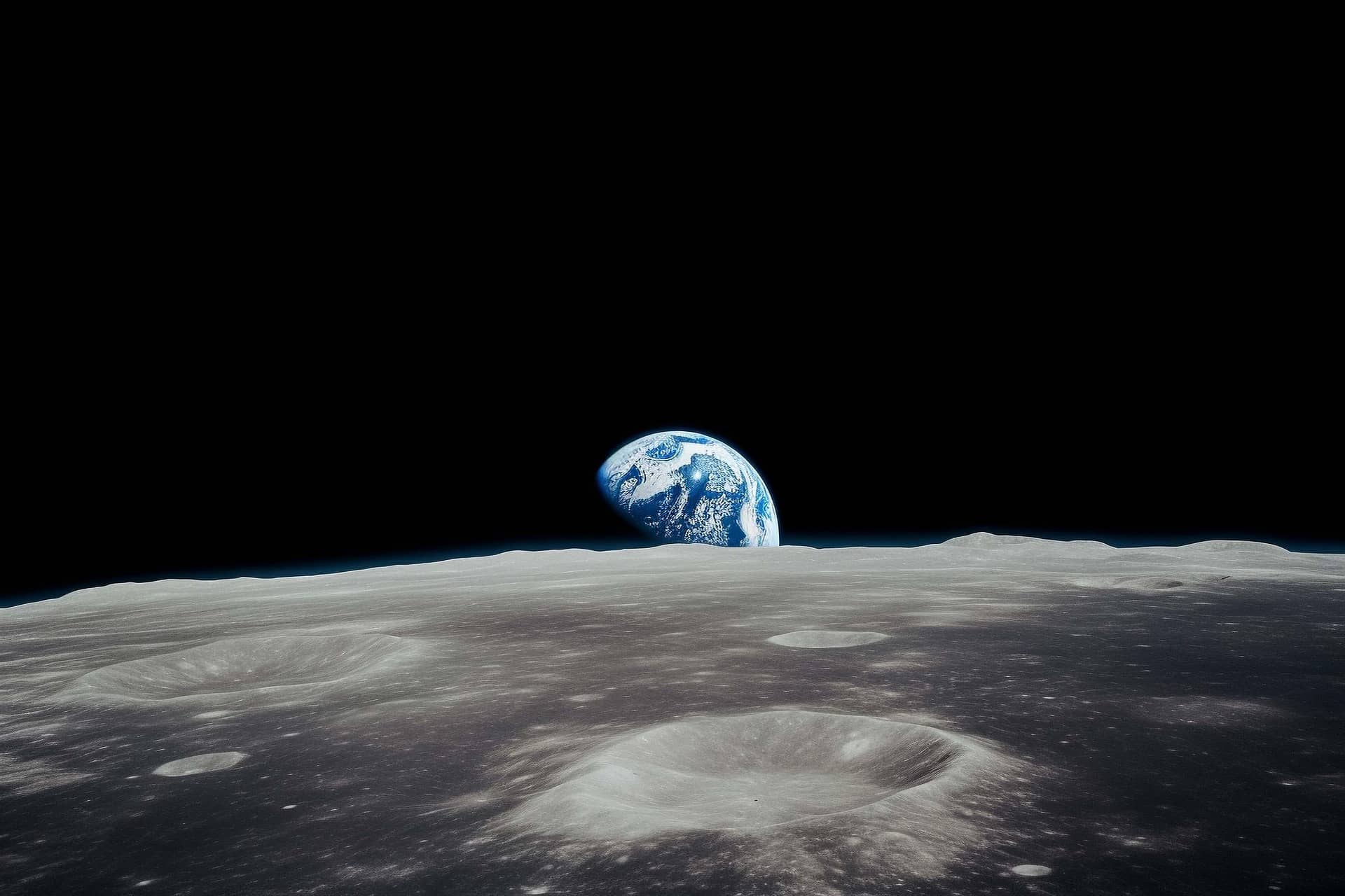 Earth rising above the cratered lunar horizon, seen from the surface of the Moon